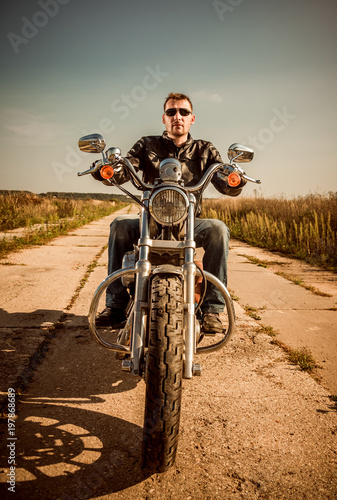 Biker in a leather jacket riding a motorcycle on the road