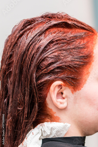 Closeup profile view on woman head after applying hair color dye in hairstylist salon.