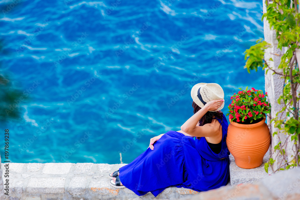 Young girl in blue dress in city of Hydra island in Greece. Summertime vacation concept