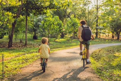 Happy family is riding bikes outdoors and smiling. Father on a bike and son on a balancebike photo