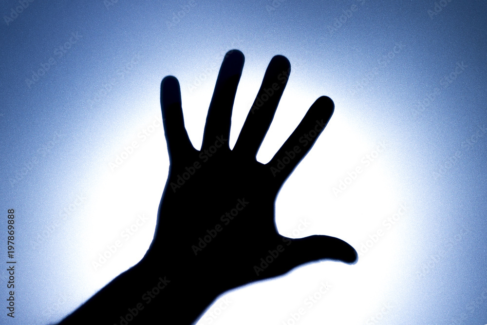 Obraz premium Silhouette of five fingers on a man's hand with a bright light spot. The concept of entreaty for help or greetings. Blue tonality.