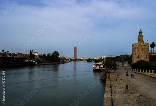View of Golden Tower (Torre del Oro), Seville Tower and Guadalquivir river in cloudy day of winter. February 2018, Seville, Andalusia, Spain.