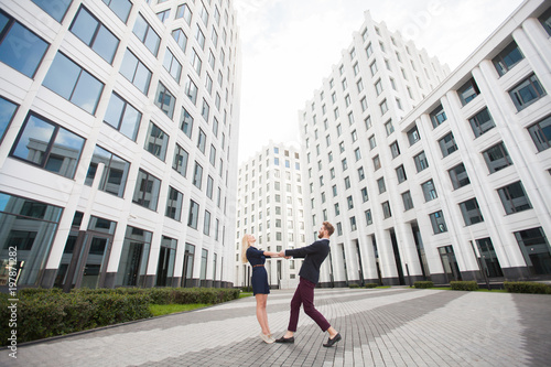 Man and woman holding hands on the background of the business center building. © Artem Zakharov