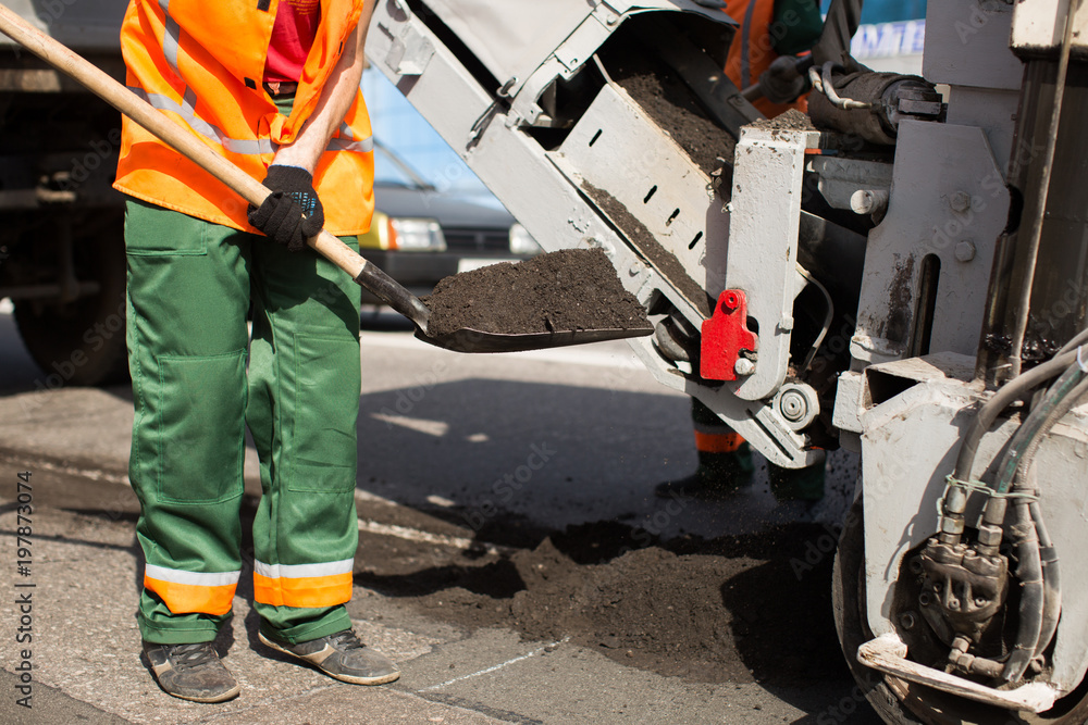 Fototapeta premium Road workers repair work. work sleeps shovel the material into the machine.