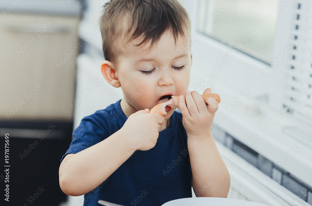 baby eating sausage in the kitchen is very charming and emotional baby eating sausage in the kitchen is very charming and emotional