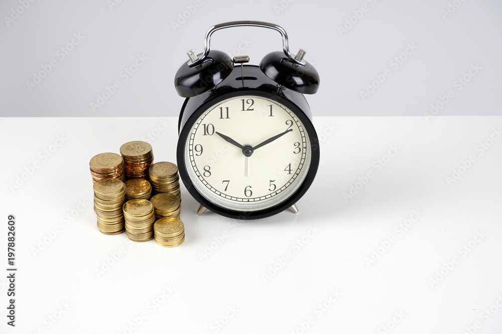 Alarm clock and coins on a white surface Alarm clock and coins on a white surface