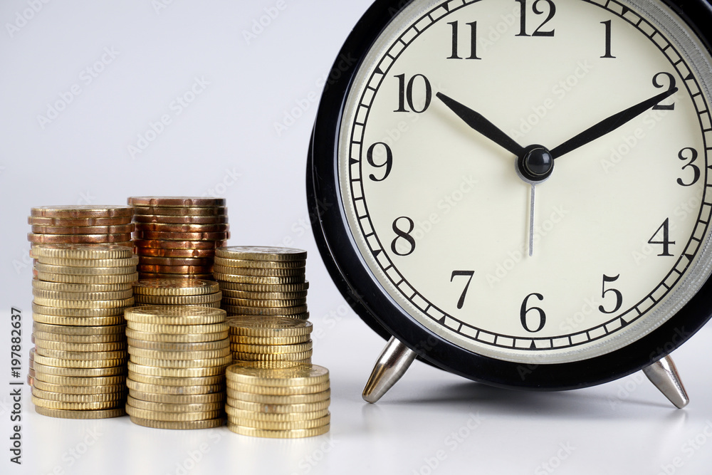 Alarm clock and coins on a white surface Alarm clock and coins on a white surface