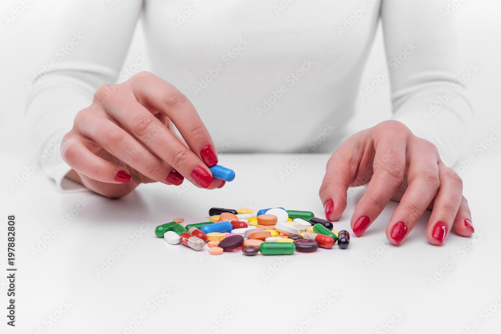 Woman chooses medicine from a handful of different color tablets.