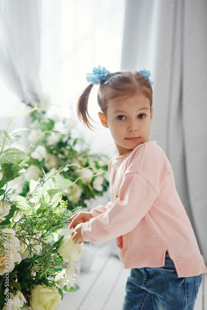 Attractive Cute little girl in a pink pullover with a bouquet of green flowers in the studio Attractive Cute little girl in a pink pullover with a bouquet of green flowers in the studio