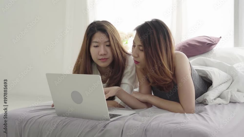 Beautiful young asian women LGBT lesbian happy couple sitting on bed hug and using laptop computer together bedroom at home. LGBT lesbian couple together indoors concept. Spending nice time at home. Beautiful young asian women LGBT lesbian happy couple sitting on bed hug and using laptop computer together bedroom at home. LGBT lesbian couple together indoors concept. Spending nice time at home.