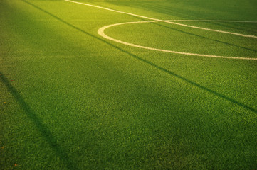 center of green football or soccer field for match or tournament with white line and morning sun light background