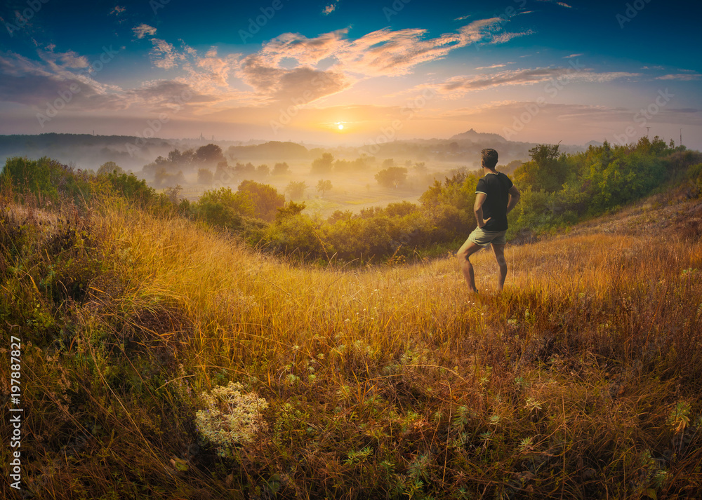 Man standing on a hill in a high graass