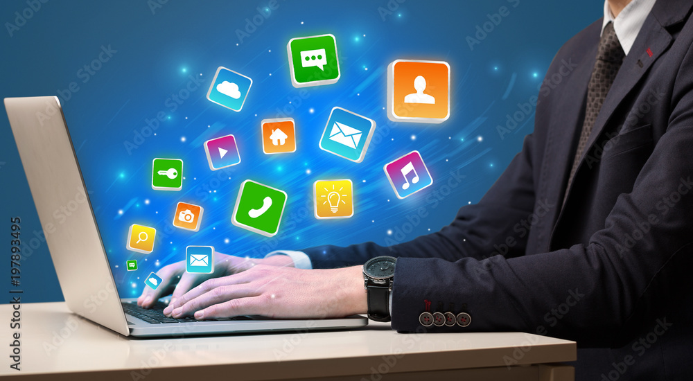 Businessman hand typing on laptop with flying application icons around
Businessman hand typing on laptop with flying application icons around