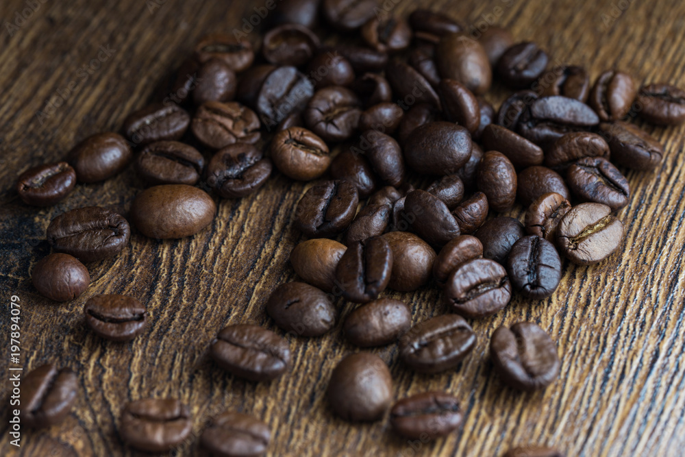 Naklejka premium Texture of coffee beans on a wooden background close-up.