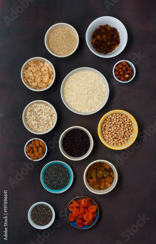 Vegetarian healthy food - different superfood, seeds and cereal on dark background, top view. Flat lay. Clean eating concept