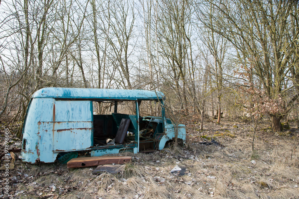 Old destroyed bus among trees on a calm day