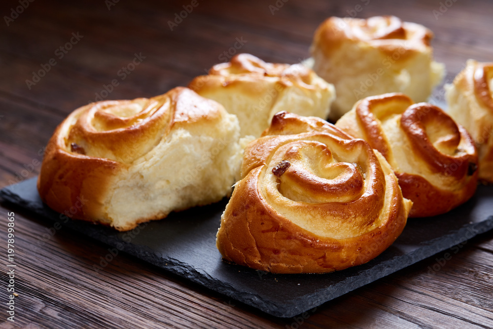 Homemade rose buns on wooden cutting board over rustic vintage background, close-up, shallow depth of field Homemade rose buns on wooden cutting board over rustic vintage background, close-up, shallow depth of field