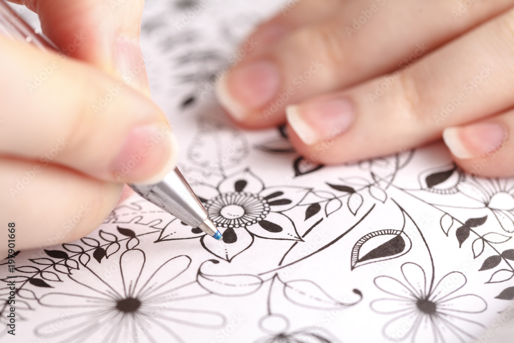 Close up adult painting book with female hand Close up adult painting book with female hand