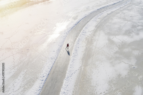 Man ice-skating of frozen lake. Aerial view photo