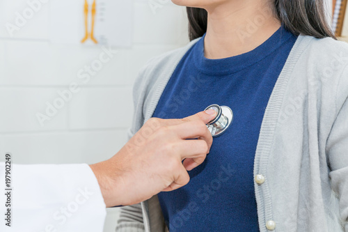 Obraz na plátně Close up of Doctor using stethoscope to exam heart and lungs of Asian woman patient