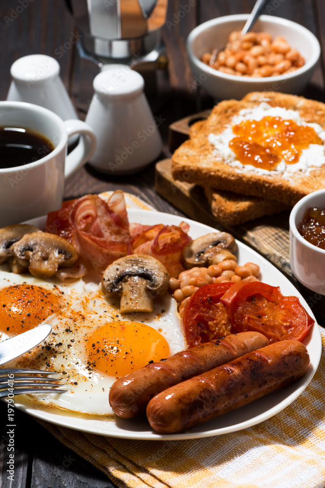 Fried eggs with bacon, sausages and vegetables, vertical closeup