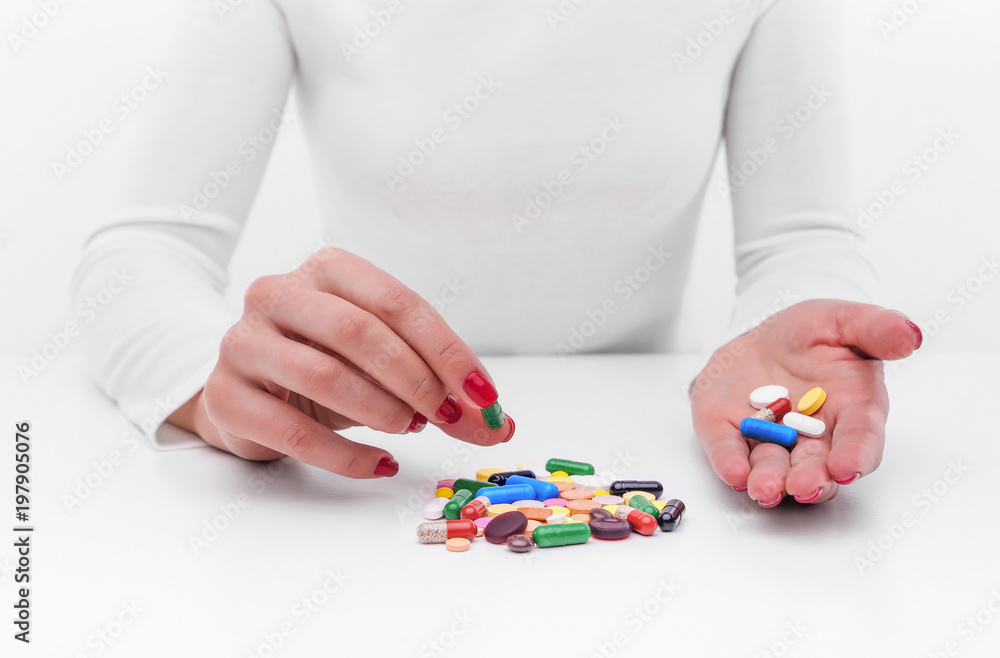 Woman chooses medicine from a handful of different color tablets.