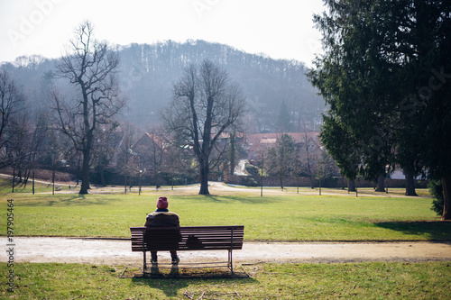 Frau sitzt im Park auf einer Bank und genießt die Sonne, Frühling