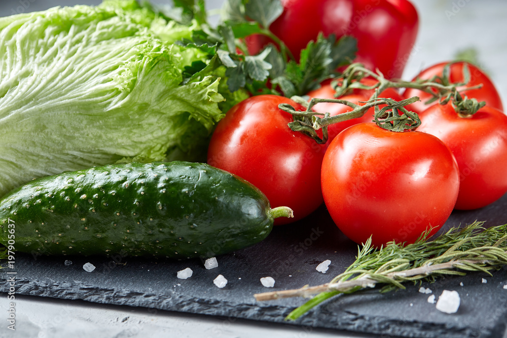 Bunch of fresh tomatoes with green leaves on stony board over white background, top view, close-up, selective focus Bunch of fresh tomatoes with green leaves on stony board over white background, top view, close-up, selective focus