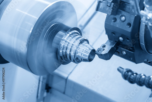 Obraz na plátně The CNC lathe machine cutting the metal cone shape part in the light blue scene