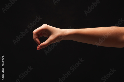 Female hand picking up something, cutout at black