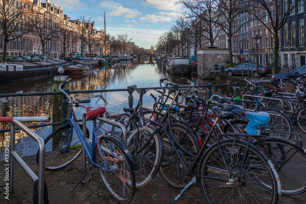 water canals in Amsterdam with a bridge in the middle and traditional architecture with bicycles