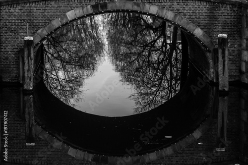 water canals in Amsterdam with a bridge in the middle and traditional architecture black and white