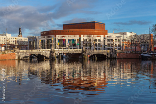 Dutch National Opera and Ballet building reflecting in canal water on a sunny day