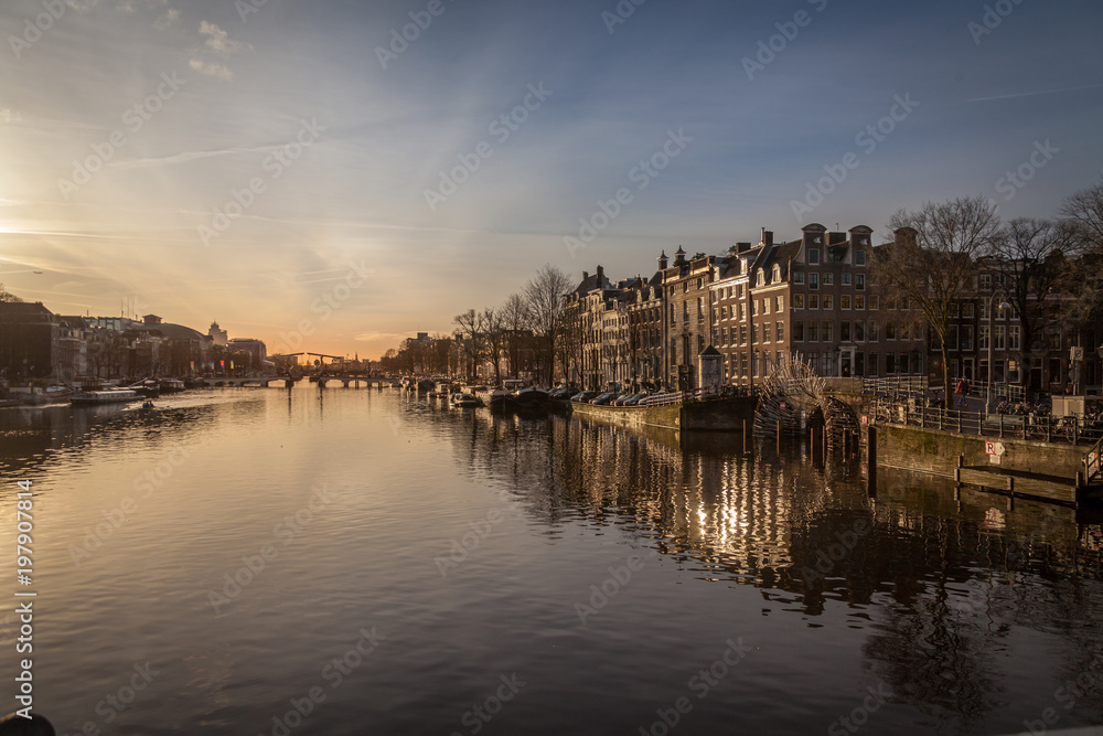 sunset in Amsterdam over river Amstel traditional architecture