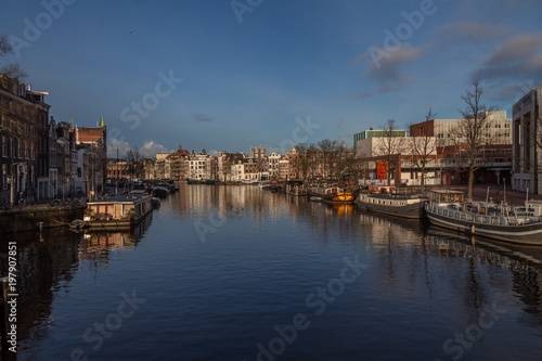 water canals in Amsterdam with  traditional architecture reflecting in the water on a sunny day