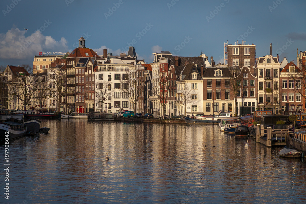water canals in Amsterdam with  traditional architecture reflecting in the water on a sunny day