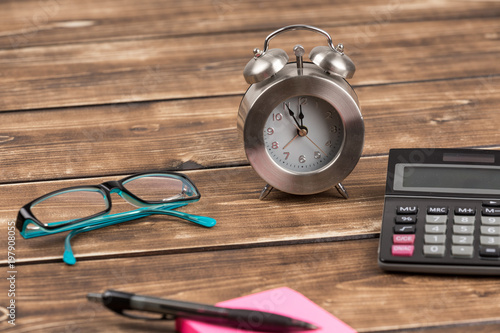 workplace with clock, paper, calculator and glasses