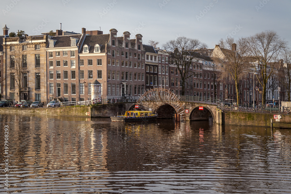 water canals in Amsterdam with a bridge in the middle and traditional architecture