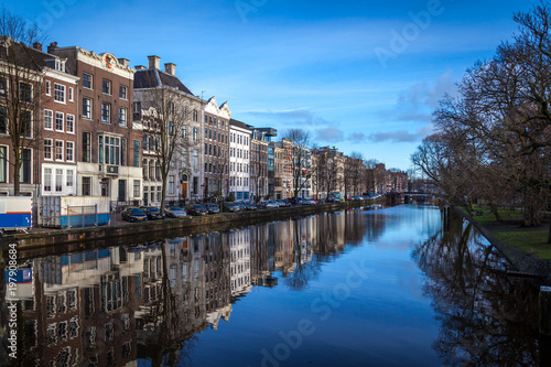 water canals in Amsterdam with traditional architecture reflecting in water on a sunny day with blue sky