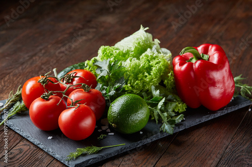 Close-up still life of assorted fresh vegetables and herbs on wooden rustic background, top view, selective focus.