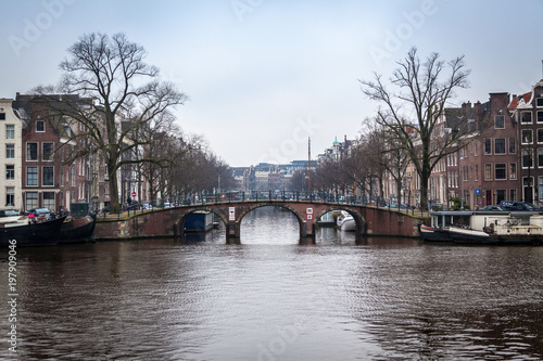 water canals in Amsterdam with a bridge in the middle and buildings on both of bridge's side 