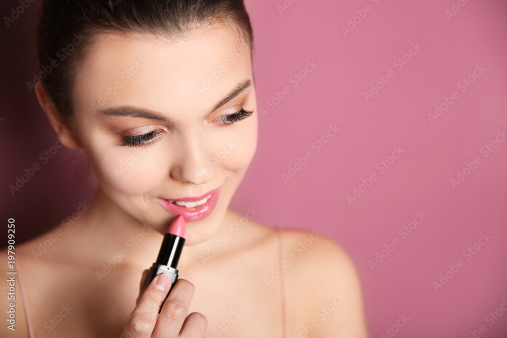 Young woman applying lipstick on color background. Professional makeup products Young woman applying lipstick on color background. Professional makeup products
