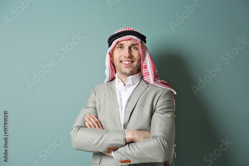 Muslim businessman in traditional clothes on color background