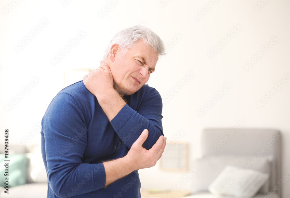 Mature man suffering from neck pain at home Mature man suffering from neck pain at home