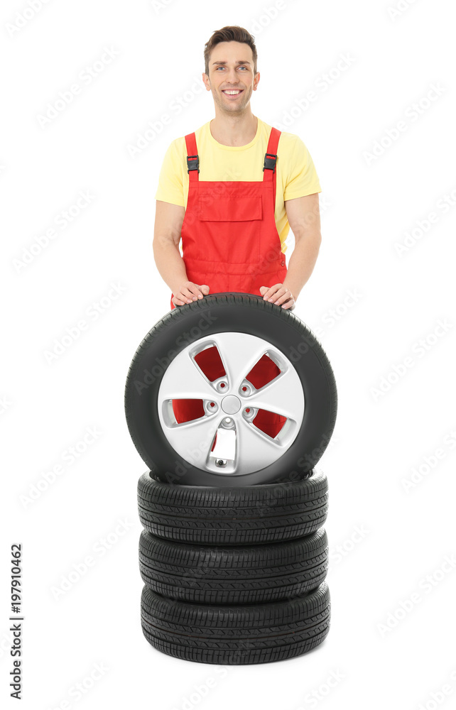 Young mechanic in uniform with car tires on white background Young mechanic in uniform with car tires on white background