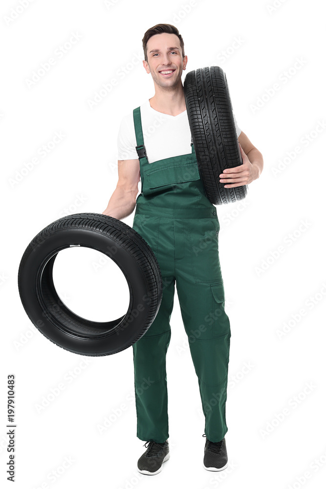 Young mechanic in uniform holding car tires on white background Young mechanic in uniform holding car tires on white background