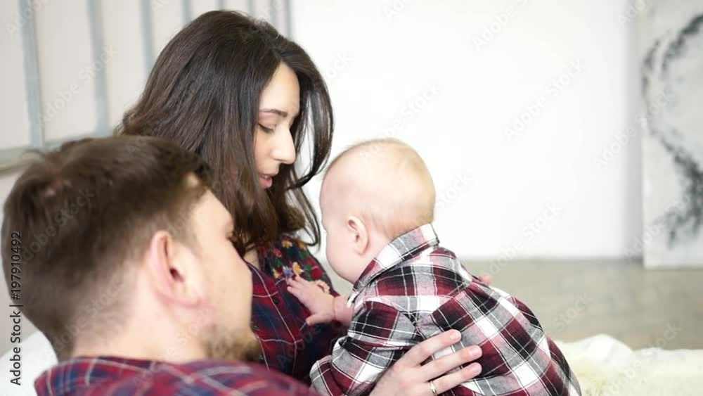 Happy parents lying with their cute baby son on bedat home in bedroom Happy parents lying with their cute baby son on bedat home in bedroom