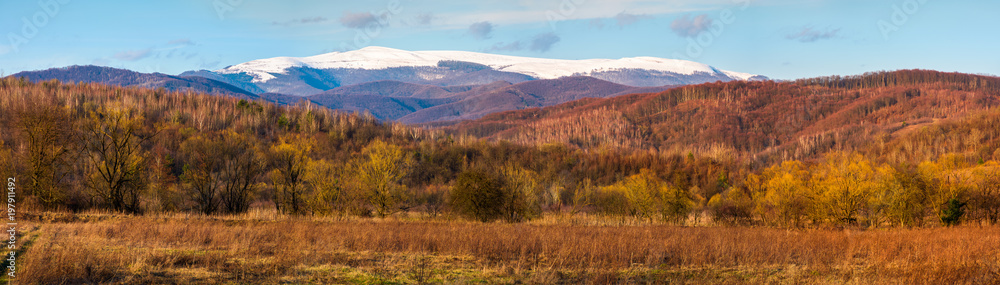 springtime countryside with snowy mountain in the distance. lovely panorama of Runa mountain in evening springtime countryside with snowy mountain in the distance. lovely panorama of Runa mountain in evening