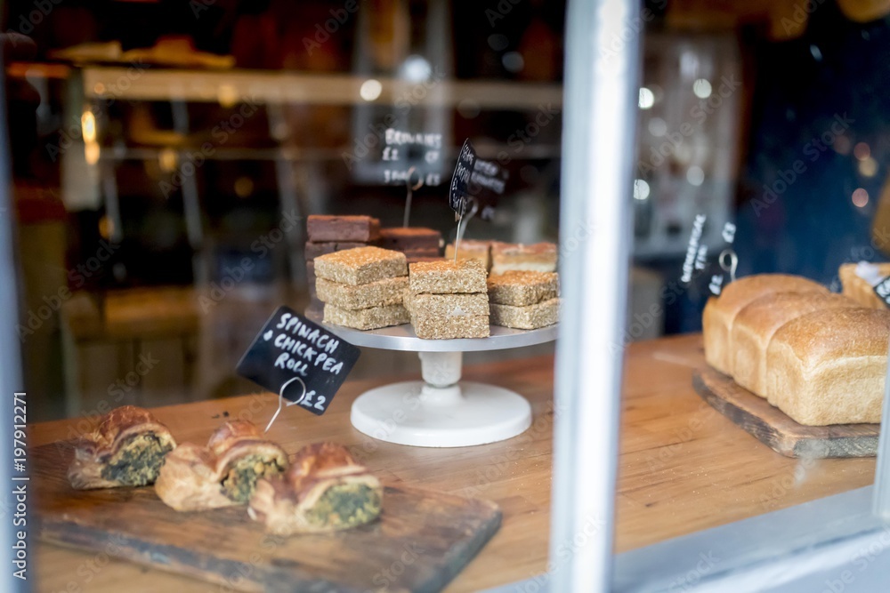 Flapjack and cake selection on a display on a cake stand in a bakery shop window