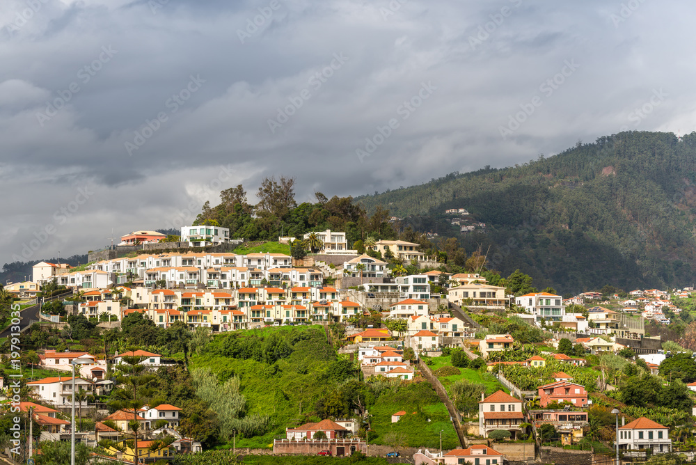 Cityscape of Funchal in cloudy rainy weather, Madeira Island, Portugal. Residential buildings on the slope.